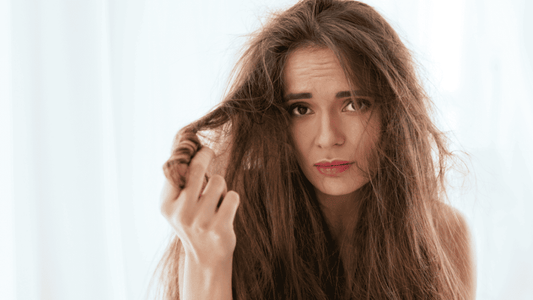 Mujer mirando con preocupación su pelo dañado y quemado por el calor de la plancha